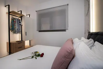 a bedroom with a white bed with a pink pillow at ALPHA SUITES in Chania Town