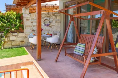 a patio with a table and chairs and a bench at Villa Portokalia Platanias in Plataniás
