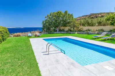 a swimming pool in a yard next to a grassy field at Villa Koule in Kalami