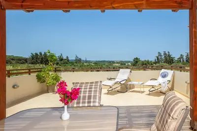 a patio with a table and chairs on a balcony at Villa Lemonia Platanias in Plataniás