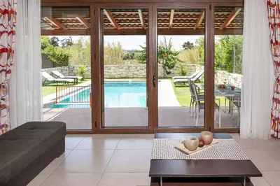 a living room with a pool and sliding glass doors at Villa Lemonia Platanias in Plataniás
