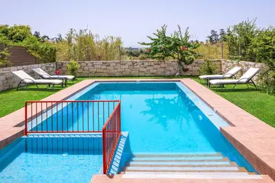 a swimming pool in a yard with chairs around it at Villa Lemonia Platanias in Plataniás