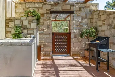 a stone building with a door and a grill at Villa Mandarin Platanias in Plataniás