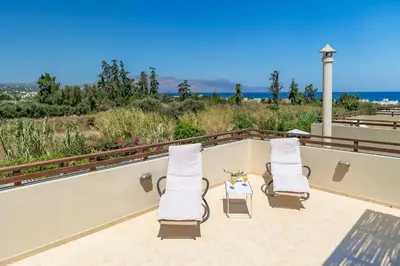 two chairs and a table on a balcony with the ocean at Villa Mandarin Platanias in Plataniás