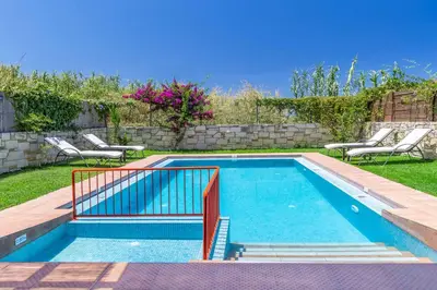 a swimming pool in a yard with chairs around it at Villa Mandarin Platanias in Plataniás