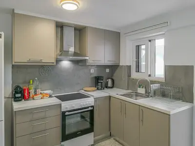 a kitchen with white cabinets and a stove top oven at Comfy flat with large terrace, Fiber internet and private parking in Chania Town