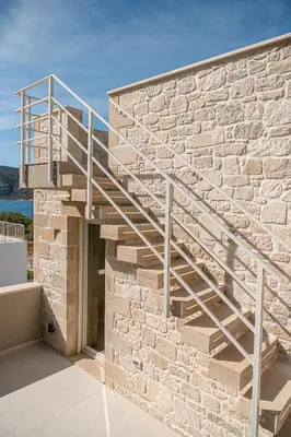 a metal staircase on the side of a stone building at Pietra Di Sabbia Villas in Palaiochóra