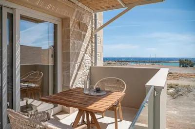 a wooden table on a balcony with a view of the beach at Pietra Di Sabbia Villas in Palaiochóra