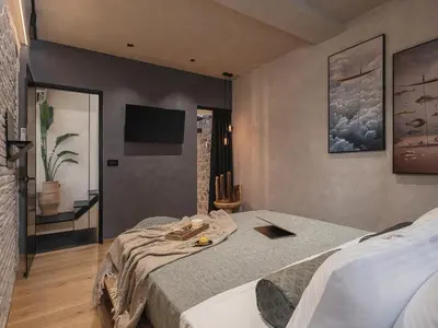 a bedroom with a bed and a flat screen tv at Mimosa Minaret Jacuzzi Old Town Chania in Chania Town