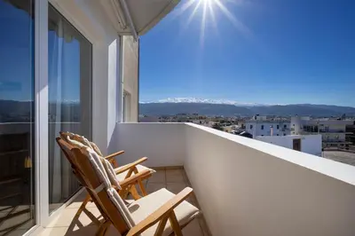 two chairs on a balcony with a view of the mountains at Purple Apartment Chania in Chania Town