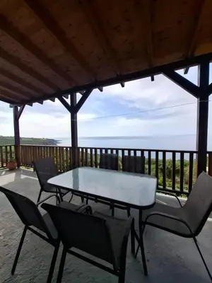 a table and chairs on a patio with a view of the ocean at Votsalo House in Khóra Sfakíon