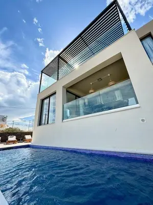 a house with a swimming pool in front of a house at Luxury Sunset Villa with Private Pool & Sea Views in Kalyves