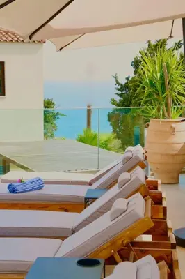 a group of lounge chairs sitting on a patio with an umbrella at Luxury Sunset Villa with Private Pool & Sea Views in Kalyves