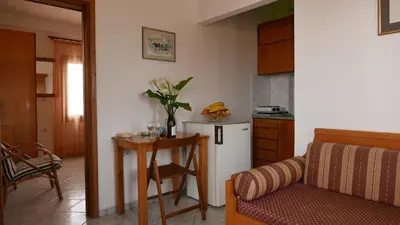 a kitchen with a small table and a refrigerator at Angela Apartments in Kato Daratso