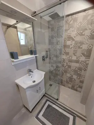 a white bathroom with a shower and a sink at Aspro Apartments in Koprána
