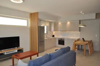 a living room with a blue couch and a kitchen at Sunny flat among olive trees, next to the beach in Módhion