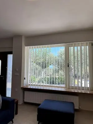 a living room with a large window with a view at Sunny flat among olive trees, next to the beach in Módhion