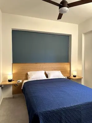 a bedroom with a large blue bed with two lamps at Sunny flat among olive trees, next to the beach in Módhion