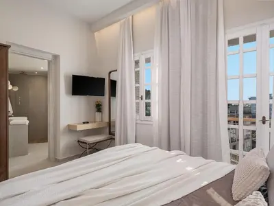 a white bedroom with a bed and a window at Casa Benedetta in Chania Town