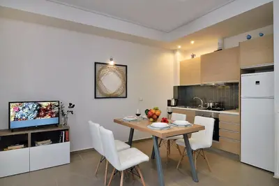 a kitchen with a table and white chairs in a kitchen at Cosy apartment near the beach in Chania Town