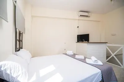 a bedroom with a white bed and a tv at Be Crete - Solis maisonette in Chania Town