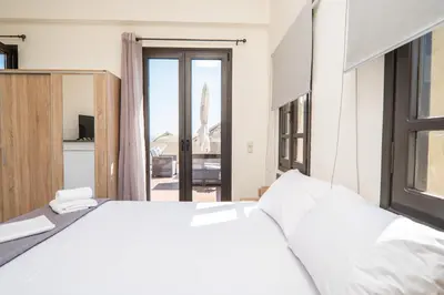 a bedroom with a large white bed and a balcony at Be Crete - Solis maisonette in Chania Town