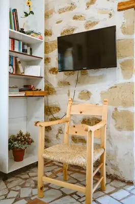 a wooden rocking chair with a television on a stone wall at Xanthippi's in Pemónia