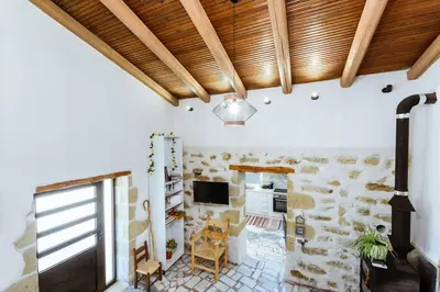 a living room with a stone wall and wooden ceiling at Xanthippi's in Pemónia