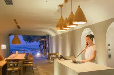 a woman talking on a phone at a counter with a laptop at The Theodore Boutique Hotel- adults only 16 plus in Agia Marina Nea Kydonias