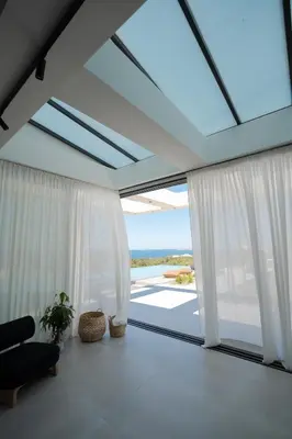 a living room with white curtains and a large window at Hygge Villa Evgenia in Kounoupidhianá
