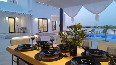 a wooden table with plates and wine glasses on it at Montis villa sea view heated pool in Daratso