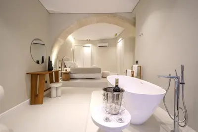 a white bathroom with a bottle of wine on a counter at Amelia Luxury Suites Old Town in Chania Town
