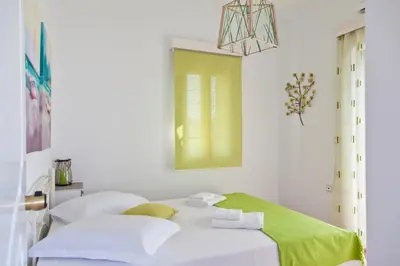 a white bedroom with a bed with a green blanket at Villa Smaragdi - Private Sea View Villa in Falasarna