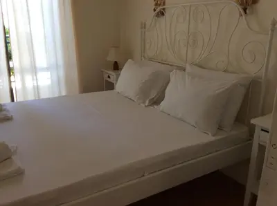 a white bed with a white headboard and white pillows at Andy's Gardens in Gerani Chanion