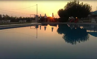a swimming pool with the sunset in the background at Andy's Gardens in Gerani Chanion