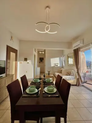 a dining room with a table and chairs and a living room at Stratos Apartment in Chania Town