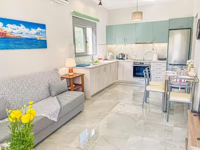 a living room with a couch and a kitchen at Newly Built House Steps from the Beach: Everything Within Walking Distance - Enjoy a Car-Free Stay in Agia Marina Nea Kydonias
