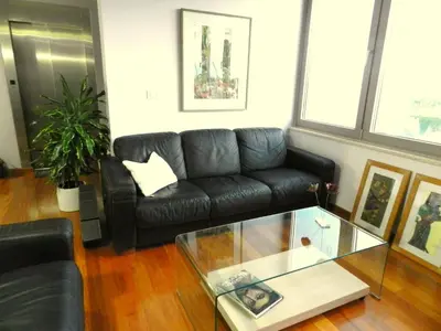 a living room with a black leather couch and a glass table at Pentari-Bitsakis House in Chania Town