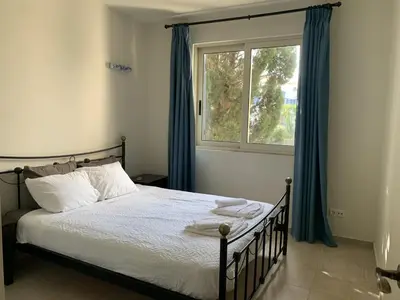 a bedroom with a bed with blue curtains and a window at Villa Elias & Casseiopia in Chania Town