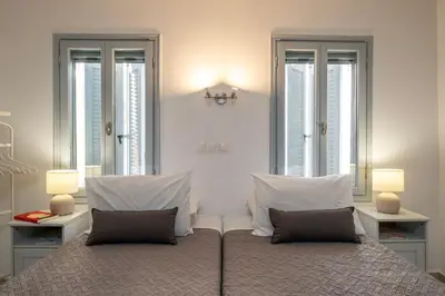 a bedroom with a large bed with two windows at s - plazza residence in Chania Town