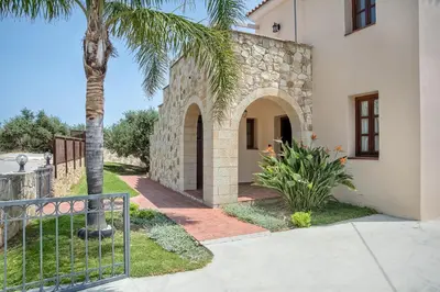 a house with a gate and a palm tree at Villa Katerina with Eco heated pool in Spiliá