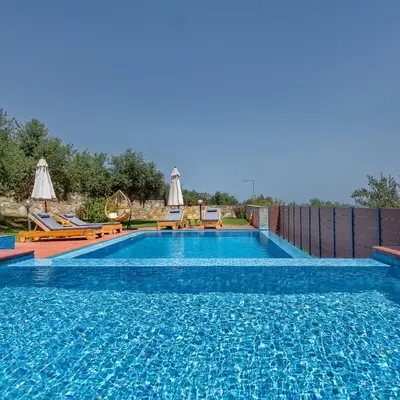 a swimming pool with blue water in a backyard at Villa Katerina with Eco heated pool in Spiliá
