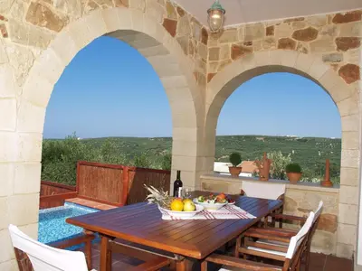 an outdoor patio with a wooden table and two arches at Villa Katerina with Eco heated pool in Spiliá