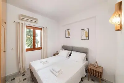 a twin bedroom with two beds and a window at Klapas by PosarelliVillas in Chania Town