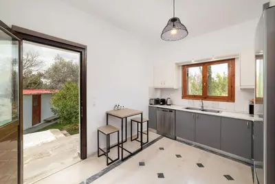 a kitchen with gray cabinets and a large window at Klapas by PosarelliVillas in Chania Town