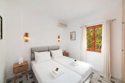 a white bedroom with a bed and a window at Klapas by PosarelliVillas in Chania Town