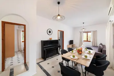 a living room with a table and chairs and a piano at Klapas by PosarelliVillas in Chania Town