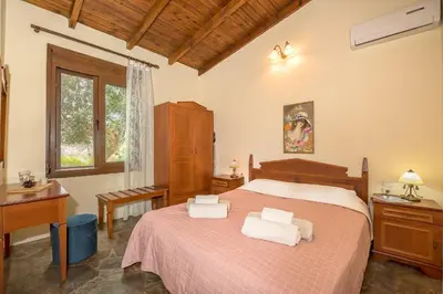 a bedroom with a bed and a desk and a window at Yiannis Cottage in Spiliá