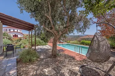 a pool with a tree next to a house at Yiannis Cottage in Spiliá