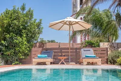 two chairs and an umbrella next to a swimming pool at Yiannis Cottage in Spiliá